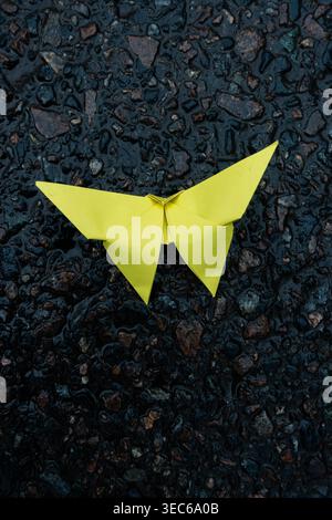 Bright yellow origami butterfly resting on mossy surface, handmade paper art symbolizing creativity, nature and delicate design Stock Photo