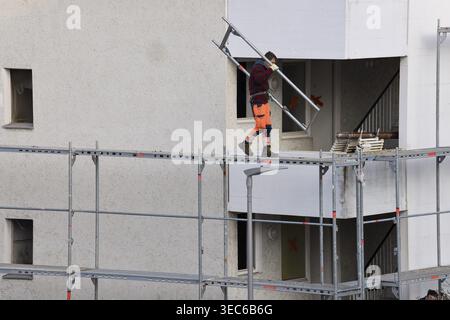 Old building with scaffolding, scaffolder carrying scaffolding, scaffolding with orange pants walking on scaffolding, demonstration of building scaffo Stock Photo