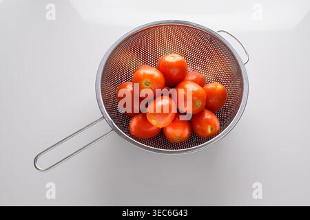 Top View of Stainless Steel Colander with Red Tomatoes on White Background Stock Photo