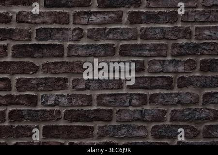 Dark brown brick wall close-up texture. Rough aged brickwork. Grungy masonry background Stock Photo