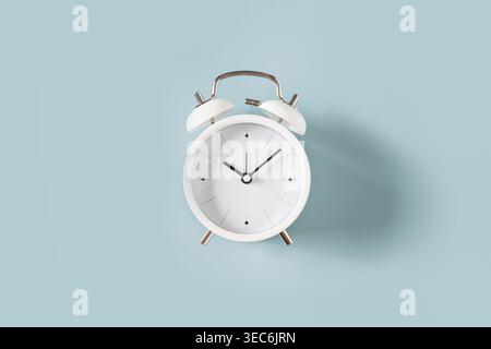 White alarm clock on blue background, minimal time management concept, schedule and productivity idea, copy space Stock Photo