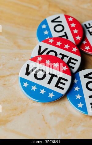 cluster of vote badges in red, white, and blue colors placed on a marble surface, symbol of elections political participation and democratic rights Stock Photo