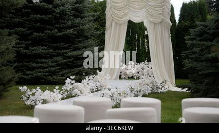 Elegant Outdoor Wedding Ceremony Setup with White Floral Arch and Aisle Stock Photo