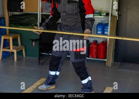 Holding wooden board in indoor workspace during installation process, construction preparation stage. DIY construction workflow Stock Photo