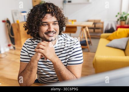 Young Indian man smiling while attending online class Stock Photo