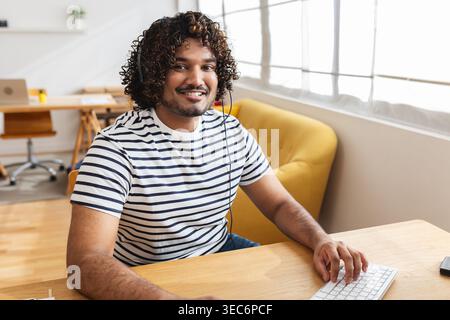 Young Indian man using computer with headset Stock Photo