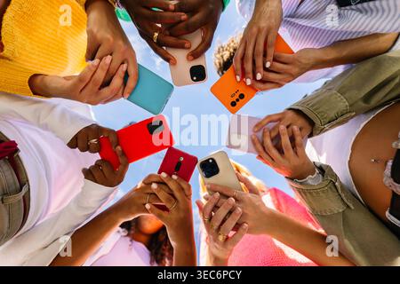 Close up of diverse young women holding colorful smartphones Stock Photo