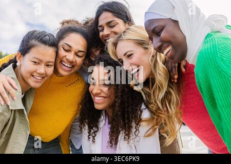 Joyful diverse women laughing and hugging outdoors Stock Photo