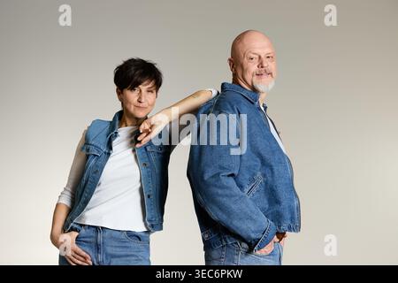 Two seniors express their love and connection through playful gestures in denim attire. Stock Photo