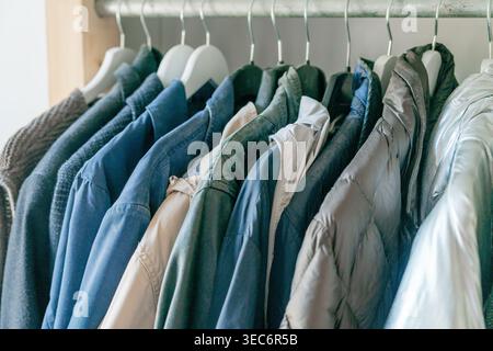 Mens clothing neatly arranged on hangers. Clean and minimal wardrobe interior. Stock Photo