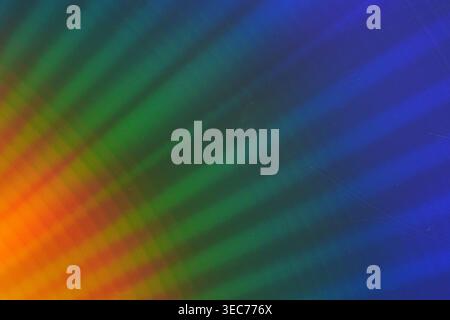 A bright display of colors creates a pattern on a surface. Rays of light spread from the center, blending together shades of orange, green, and blue d Stock Photo