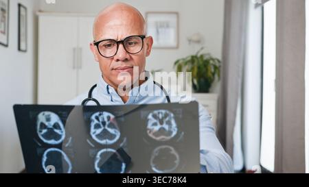 Doctor Reviewing Brain Scan X-Ray Film in Clinic Office With Stethoscope and Serious Expression Stock Photo