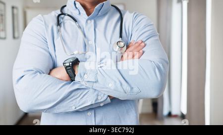 Confident Male Doctor With Stethoscope And Crossed Arms In Medical Office Setting Stock Photo