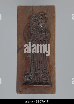 Double-sided gingerbread mold. Obverse: couple holding hands—a woman in a richly decorated long dress with a hat, and a man in a caftan with a short wig; both in 18th-century costume; plant-element decoration at the bottom. Reverse: three empty rectangles. Woodcarving; applied art; genre scene with female and male figures, couples in love, plant motifs. Rectangular. 18th–19th century, Province of Silesia 1742–1918. Height 20 cm, width 8.7 cm., A vertical rectangular wooden panel with a carved relief of two standing human figures close together, the carving showing a darker brown against a Stock Photo