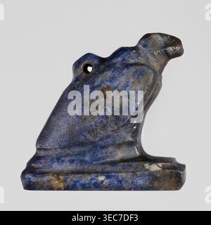 Amulet - vulture, Gołuchów Greater Poland Voivodeship, vultures, birds, pendant, sitting on a base, with a pendant on the back, ca. 1550–1069 BC; New Kingdom, Egypt, amulet, height 1.3 cm, width 1.8 cm, A small carved object shaped like a stylized animal sitting on a rectangular base, with a rounded head, a short beak-like snout, and a small hole near the top; the surface shows a mottled mix of deep blue, lighter blue, gray, brown, and some white spots, with visible texture and areas of wear and slight pitting. Stock Photo