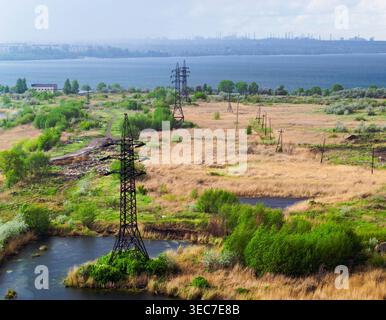 Thunderclouds over the lake and power lines in the field Stock Photo