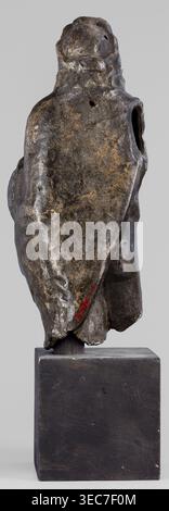 Figurine of Sylvanus in goat skin, with a pine wreath and a pine branch in his hand, figurines from a mold, Silvanus myth., 2nd century, Gaul France, figurine, height 23 cm, width 10 cm, depth 7.3 cm, weight 1.474 kg, A weathered sculptural form mounted on a rectangular block base, shown from the back. The sculpture has an irregular, organic surface with a draped, cloak-like outline and a rounded top suggesting a head. The surface shows varied textures with rough, pitted areas and smoother worn patches. Visible colors include dark brown, black, and patches of muted golden-brown and gray on the Stock Photo