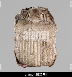 Scarab with naturalistic modeling; protective amulet depicting a sacred animal; Late Period, 26th Dynasty, 664–525 BC, Egypt; amulet scarab; height 4 cm, width 2.8 cm;, A single carved object resembling a rounded, symmetrical form with a textured surface and vertical grooves on its lower portion, showing a few irregularities and chips around the edges; the top area has a raised central section flanked by curved, ribbed elements and a beaded border where the upper and lower sections meet; the surface shows a weathered, pitted texture with small rough spots and worn details; visible colors Stock Photo