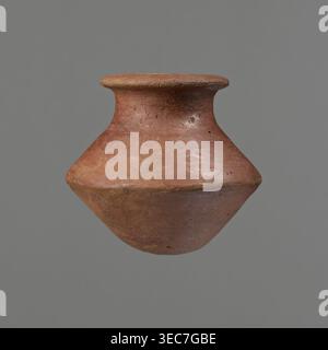 Vessel, Egyptian pottery ceramic clay vessel, c. 1650–c. 1550 BC Second Intermediate Period, Edfu, vessel, height 7.4 cm, rim diameter 5.5 cm, belly diameter 8.2 cm., A single terracotta vessel with a rounded, bulbous body and a flaring neck and rim floats against a plain grey background; the surface shows an earthy reddish-brown color with patches of lighter tan and ochre, a slightly rough and weathered texture with visible small pits, scratches, and subtle variations in sheen, and the rim appears flatter and slightly darker than the middle of the vessel. Stock Photo