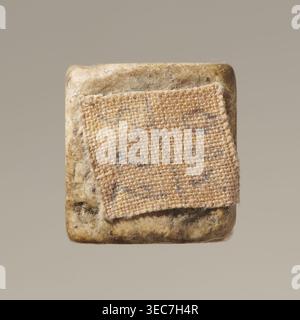 Dice, six-sided dice for the game of dice, points 1–6 shown as hollow circles and dots, material unspecified, place of origin unknown, varia, height 0.9 cm, width 1.1 cm, depth 0.9 cm, A close-up of a square object with rounded corners showing a textured fabric patch adhered to its surface; the object surface is mottled with beige, tan, brown, and gray tones, and the fabric patch is woven with visible fibers in shades of light tan and beige with subtle gray flecks, frayed edges, and a slightly raised, coarse texture against the smoother, speckled background. Stock Photo