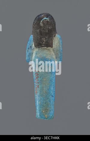 Ushabti Henut-netjeru. Mummy-shaped figurine shabti, height 9 cm, width 3 cm, depth 1.5 cm. Third Intermediate Period, 21st Dynasty, ca. 1069–ca. 945 BC. Arms crossed on the chest, right over left, holding hoes in both hands; a rectangular basket on the back with painted tools. Wearing a usech necklace and wide bracelets painted jewelry. Long, smooth three-part wig covering the ears; round face with large eyes; wig and facial details painted. Painted inscription in one column on the front of the legs reading: Shd Osiris Henut-netjeru, justified by the voice., The image shows a small human- Stock Photo