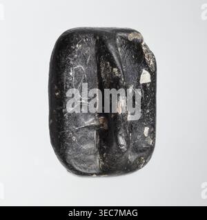 Rectangular stamp seal with a handle in the form of a protruding ridge along the axis of the seal with a crosswise drilled hole. On a rectangular base with rounded corners is a schematic representation of a demon, in human form and with wings instead of arms. Unspecified filler elements are on the sides of the demon. Materials/technique: seal. Date: c. 1650–c. 1350 BC Late Bronze Period. Place of manufacture: Northwest Syria; find region: Near East. Dimensions: height 1.7 cm, width 4.2 cm, depth 3.2 cm., A single smooth, irregularly shaped dark object with a mostly black surface and a few Stock Photo