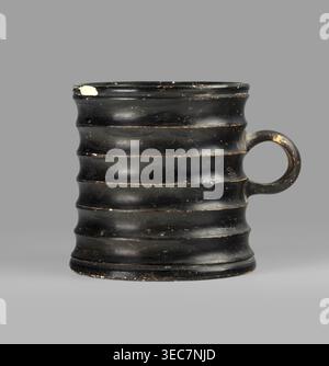 Dice cup, Gołuchów Greater Poland Voivodeship. Greek ceramic dice game cup, 5th century BC, Attica. Vessel with small flat slightly concave bottom, slightly tapered walls, distinct rim and foot; outer surface decorated with seven wide ribs. Object entirely covered with black varnish shiny but in places matte; traces of turning visible under varnish, except for a small fragment on the inner surface and the outer surface of the bottom, which has a concentric decoration. Condition: spout slightly chipped in one place; surface shows dirt and secondary losses; varnish worn on rib ridges. Clay color Stock Photo