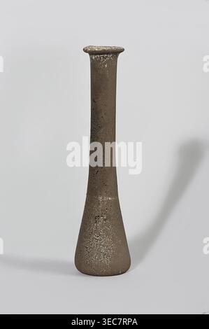 Bottle; maker, 1st century BC–1st century AD; Egypt; vessel., A tall, narrow ceramic vessel with a flared rim and a rounded, tapered base stands against a light gray background, showing a textured surface with speckled areas; the object is primarily brown with lighter beige and off-white speckles and darker brown spots, and it casts a soft shadow to the right on the pale background. Stock Photo