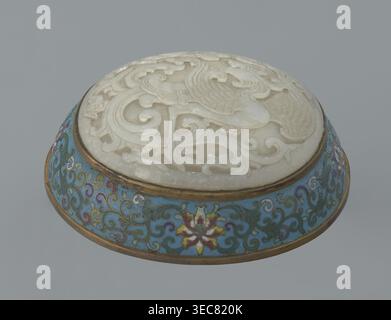 Box with a lid., Chinese, Qing dynasty, Qianlong period, 18th century. Cloisonné enamel on metal with a slightly convex bas‑relief grayish jade plaque on the lid. Oval, spheroidal box based on a ring foot, divided halfway into container and lid. Lid plaque depicts a fenghuang phoenix or peacock with a sun among clouds; the sun is in the upper left surrounded by a silk ribbon. Motifs and styling reference mandarin square emblems peacock denoting third civilian rank; sun referring to imperial authority. Rounded sides of both container and lid decorated with multi‑colored lotus tendril stripes on Stock Photo