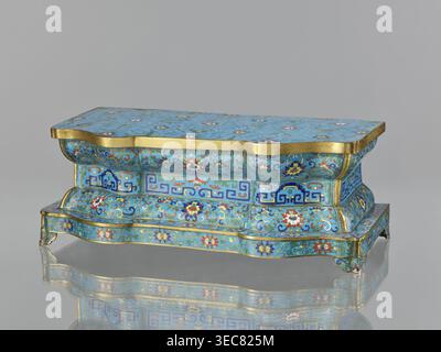 Wall pedestal; creator, cloisonné enamel; decoration: flowers on a turquoise background with a grid of cracks cracked ice, floral tendrils on the profiles, and a central band with geometric motifs; plant and floral and geometric ornament; Qing dynasty 1644–1911, 18th century; China; height 13.5 cm, width 36.6 cm, depth 18.5 cm., A small ornate rectangular box with a wavy, scalloped profile sits on a reflective surface, showing a mirrored underside. The box is covered in a bright turquoise-blue enamel background with intricate floral and foliate patterns in colors including blue, red, white, Stock Photo