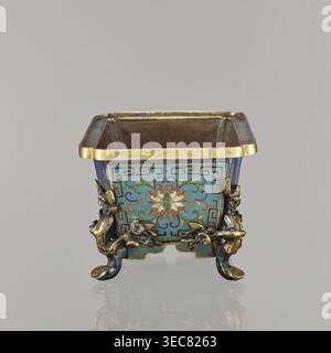 Flower pot incense burner on four legs, cloisonné enamel; decoration: lotus tendril on a turquoise background; legs in the shape of flowered trunks plum branches made of gilded bronze; motifs include lotuses, plum trees, cracked ice, meander; jardinère form; 18th century, Qing 1644–1911, China; vessel; height 9.5 cm, width 17.2 cm, depth 12.0 cm., A small square metal container with an open top sits on a reflective surface, showing a decorative exterior in blue, turquoise, gold, red, white, and green. The upper rim is gold, and each side panel features a central floral motif with swirling Stock Photo
