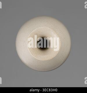 Vase on saucer. Vase made of stoneware or thick porcelain?, ovoid with a long cylindrical neck flaring at the spout; light cream white matte glaze covered with fine cracklework. 19th century, Japan, Edo 1603–1868. Ceramics; bottles/vessel. Height 24.1 cm; diameter 8.6 cm; weight 0.65 kg., A top-down view of a round ceramic vessel with a central circular opening, showing a smooth, slightly textured surface with fine crackle patterns; the vessel is primarily off-white to cream with subtle beige tones, and the interior of the opening appears dark, almost black; the background is a flat medium Stock Photo