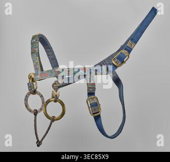 Bit, Chinese; Qing dynasty 1644–1911; cloisonné enamel on copper with leather ribbon and bronze; riding equipment element horse tack decorated with fish and plant ornament; 18th century, China; height 20.0 cm, width 7.0 cm., A decorative harness with blue fabric straps and brass buckles is suspended against a gray background; the harness features enamel panels in a row along the browband and cheekpieces with colorful painted scenes and motifs in colors including blue, green, red, white, and gold; two metal rings hang from the lower fittings, one ring with an enamelled outer edge in similar Stock Photo