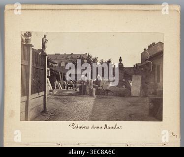 Courtyard of Mancel's House View of Jan Józef Manzel's stonemasonry and sculpting workshop, photograph by Karol Beyer 1818–1877; depicts Jan Józef Manzel 1806–1875. Subjects: sculptors' workshop, tombstones. Date: 1861–1863. Place: Chłodna, Warsaw Masovian Voivodeship. Medium/details: photographic print; nature photography; print size 5.7 × 9.2 cm; backing 11.3 × 8.8 cm., The image shows a courtyard scene bordered by a pale beige mat with a darker photograph centered within it; the photograph depicts an outdoor area with cobblestone ground, a gated wooden fence on the left topped by a small Stock Photo