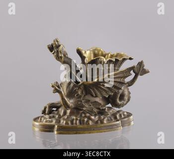 Spirit lamp in the form of a two-winged dragon on a four-leaf oval base. Between the wings is a container; the mouth holds a hole for the wick and a side hole for pouring spirit. According to a catalogue entry, it is an oil lamp and a very old one. Because of the relatively large distance from the bottom of the container to the mouth, the burner could not be fired with oil which has poor capillarity; most likely the lamp was fired with spirit, and the container between the wings was used to hold cigarettes. 2nd half of the 19th century, Polesie. Materials: bronze. Dimensions: height 15.4 cm, Stock Photo