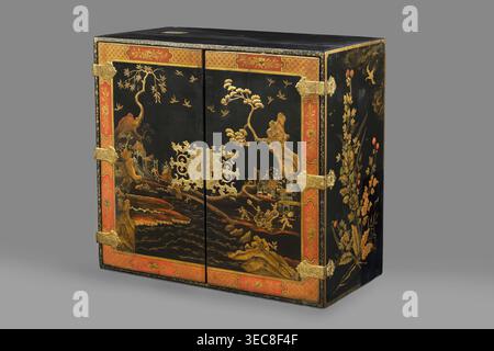 Cabinet, origin unknown, chinoiserie decoration with flowers, birds, trees, rocks, genre scenes against a landscape background, buildings, Chinese figures, bridges, geometric ornament, plant decoration; circa 1725, possibly Dresden; furniture storage cabinet; height 76 cm, width 85.5 cm, depth 41.5 cm., A rectangular wooden cabinet with a black lacquered surface decorated with gold-painted landscape scenes and floral motifs, featuring a central pair of doors with ornate gold metal hinges and an elaborate gold metal escutcheon; the doors and outer edges are framed with a decorative red border Stock Photo