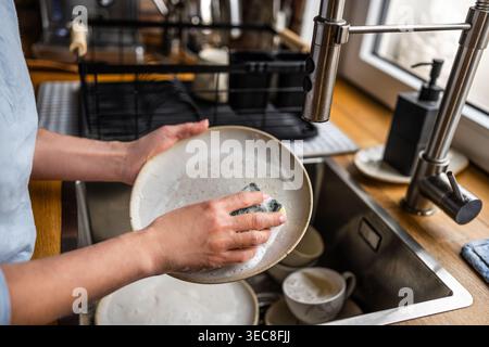 Woman's Hands Washing Dishes At Home In The Kitchen Stock Photo