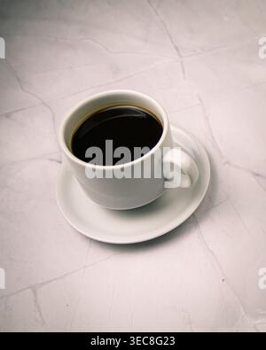 Black coffee cup top view on light marble, clean minimalist composition with copy space conveying routine, calm and everyday moment. Stock Photo