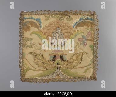 Embroidered pall. Embroidery on silk fabric. In the center is a large palmette stylized flower on a base; large leaves grow from the palmette and base with branches bearing small flowers on the sides. Edges trimmed with narrow silver bobbin lace. Composition indicates it was made from a fragment of a larger embroidered fabric. 18th century, Poland. Liturgical parament. Height 22 cm; width 20 cm., A square embroidered textile with ornate scalloped metallic trim around the edges, showing a large stylized floral motif at its center rendered in shades of tan, beige, gold, green, blue, pink, and Stock Photo