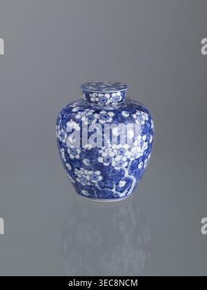 Ginger vessel with lid; Chinese; Qing dynasty (1644–1911); 19th century; spice vessel; decorative vessel; cracked-ice ornament; plum trees; porcelain vessel; height 17.5 cm, width 14.0 cm, A ceramic jar with a lid sits on a reflective surface, showing a rounded body and a short neck topped by a flat circular lid; the jar is decorated with a dense floral pattern in deep blue against white, with stylized blossoms and branches covering its curved surfaces, and the same blue-and-white floral motif appears on the lid; the background and surface are shades of gray, and a soft reflection of the jar Stock Photo
