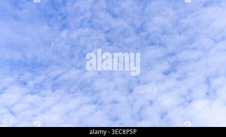Soft clouds drift across a serene, pale blue sky. White masses gently float, creating a calm, dreamlike atmosphere. No people, animals, or plants dist Stock Photo
