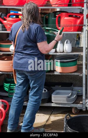Woman choosing a plastic watering can from a hardware shop. Stock Photo