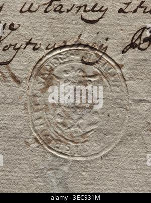 Oval seal impression of the town of Błonie, Masovian Voivodeship. On the decorative shield is the Godziemba coat of arms. Illegible inscription on the rim. 1779. Seal, dimensions 1: 31.5 mm; dimensions 2: 35.5 mm., A close-up of textured, off-white paper showing an embossed oval seal with raised ridges and worn inner details, surrounded by cursive ink markings in dark brown; the paper surface has a fibrous, slightly rough appearance with subtle brownish stains and smudges, and the overall color palette includes shades of beige, cream, light tan, and dark brown. Stock Photo