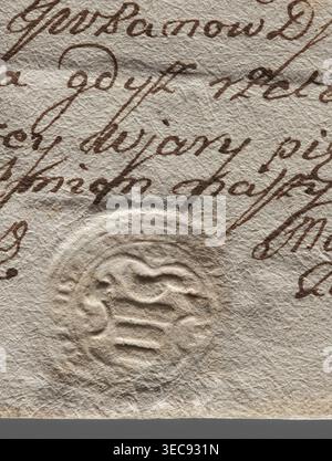 Round seal impression of the town of Biłgoraj, Lublin Voivodeship. On the decorative shield the Korczak coat of arms, above it a swan facing left. Illegible inscription on the rim. 1770, Poland., A close-up of aged textured paper showing a group of flowing handwritten strokes in brown ink across the surface and a circular embossed seal pressed into the paper; the paper is off-white to beige with visible creases and fibrous texture, the ink is a warm brown, and the embossed area casts subtle shadows in light beige and cream. Stock Photo
