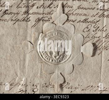 Round seal impression of the town of Brodnica, Chełmno Voivodeship. On a Renaissance shield, a left hand. On the sides, the letters PR-VS. Inscription around the rim: +, + CIVITATIS + STRASBU, 1578, Poland. Seal., A close-up of textured, off-white paper with a raised, scalloped seal affixed in the center; the seal is made from similar-colored paper and shows an embossed circular design. The background paper has a worn, fibrous surface with visible creases and wrinkles. Around and beneath the seal are flowing, handwritten strokes in a dark brown ink, visible as cursive lines and loops. The Stock Photo