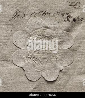 Oval seal impression of the town of Opalina. In the decorative crowned cartouche, an illegible drawing. An illegible inscription in the rim. 1788, Poland, seal, dimensions 1.37 mm, dimensions 2.42 mm, A close-up of a textured, off-white paper surface showing a scalloped, flower-shaped paper seal pressed into the sheet, with visible embossing patterns and concentric circular ridges. The paper and seal are shades of beige and cream with subtle darker beige shadows in the creases and indentations. A few small brownish spots and marks appear on the paper and seal, and there are several areas of Stock Photo