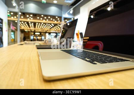 High-Tech Laptops Displayed in Modern Retail Environment Featuring Bright Lights and a Stylish Wooden Counter for Contemporary Shopping Experience Stock Photo
