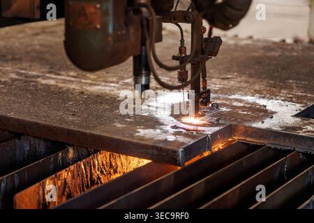 CNC plasma machine cutting thick steel plate with sparks in workshop. Industrial engineering and metal processing operation. Stock Photo