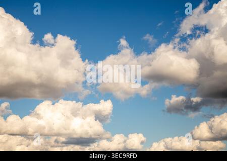Fluffy white clouds float gracefully in a blue sky during mid-afternoon, creating a peaceful atmosphere Stock Photo