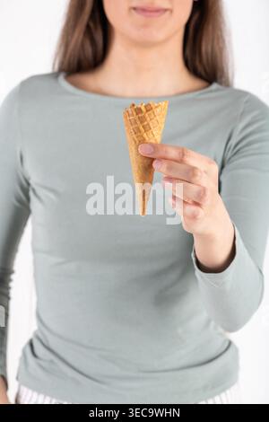 Woman's hand holding a single empty ice cream cone Stock Photo